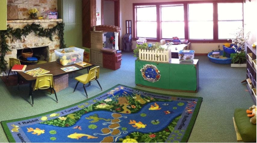 Classroom with a play rug, small table and chairs, and large windows