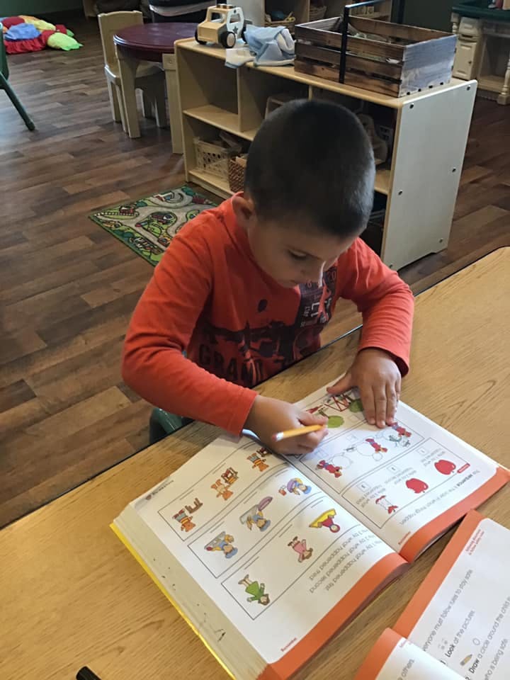 Child writing in an open workbook at a table
