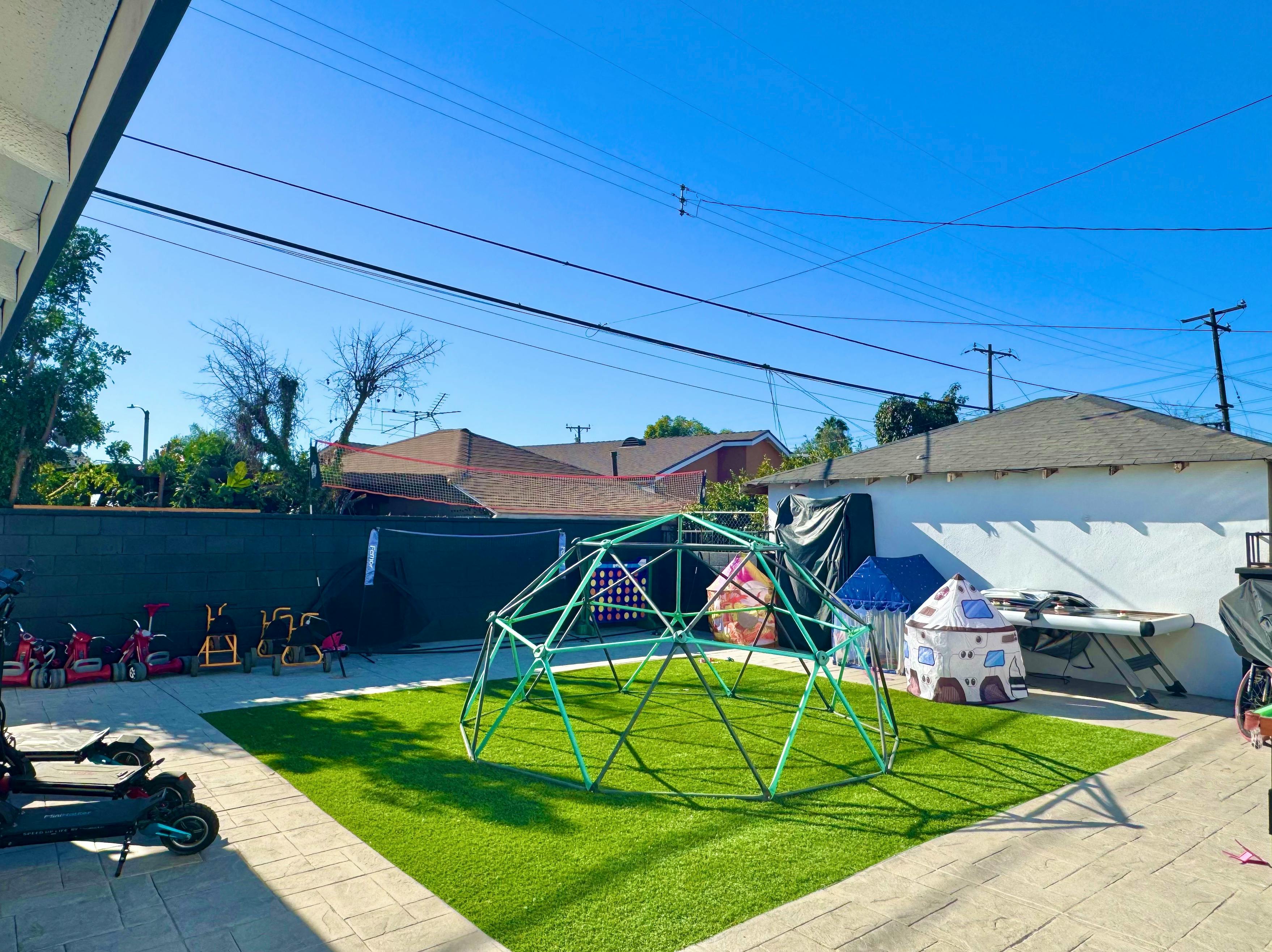 Backyard with a green geodesic dome climber on artificial turf