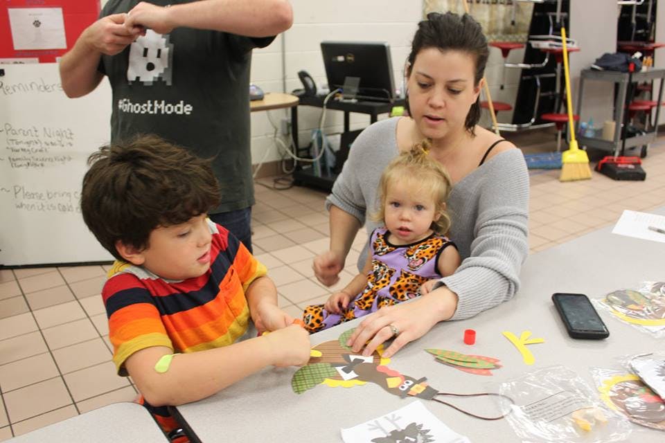 Person and two children crafting at a table