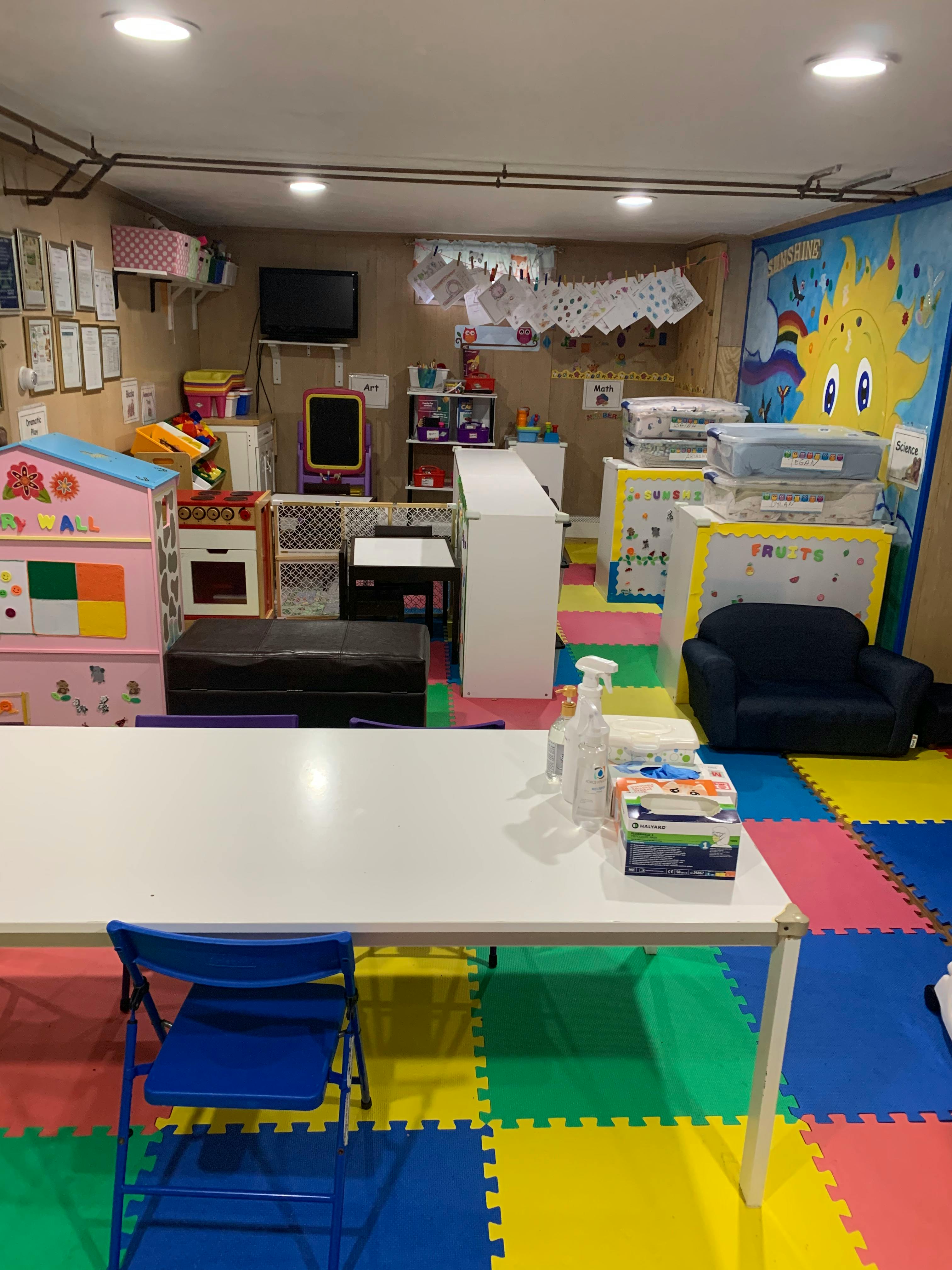 Playroom with colorful floor mats, toys, and a white table