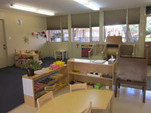 Classroom with small tables, chairs, and shelves