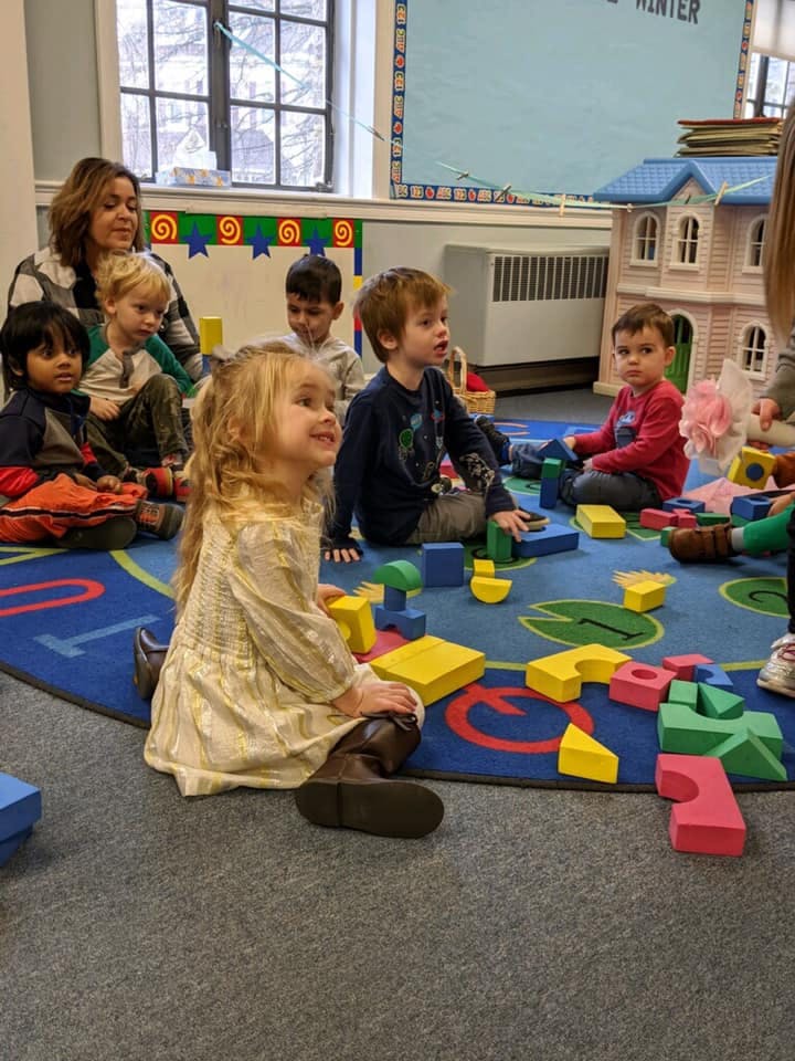 Adult and children sitting on a rug playing with blocks