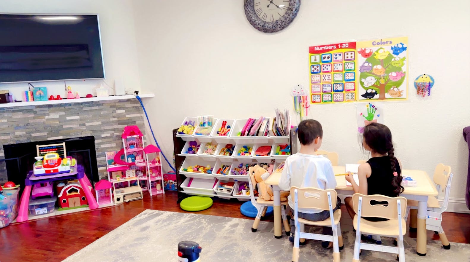 two children drawing at a small table in a playroom