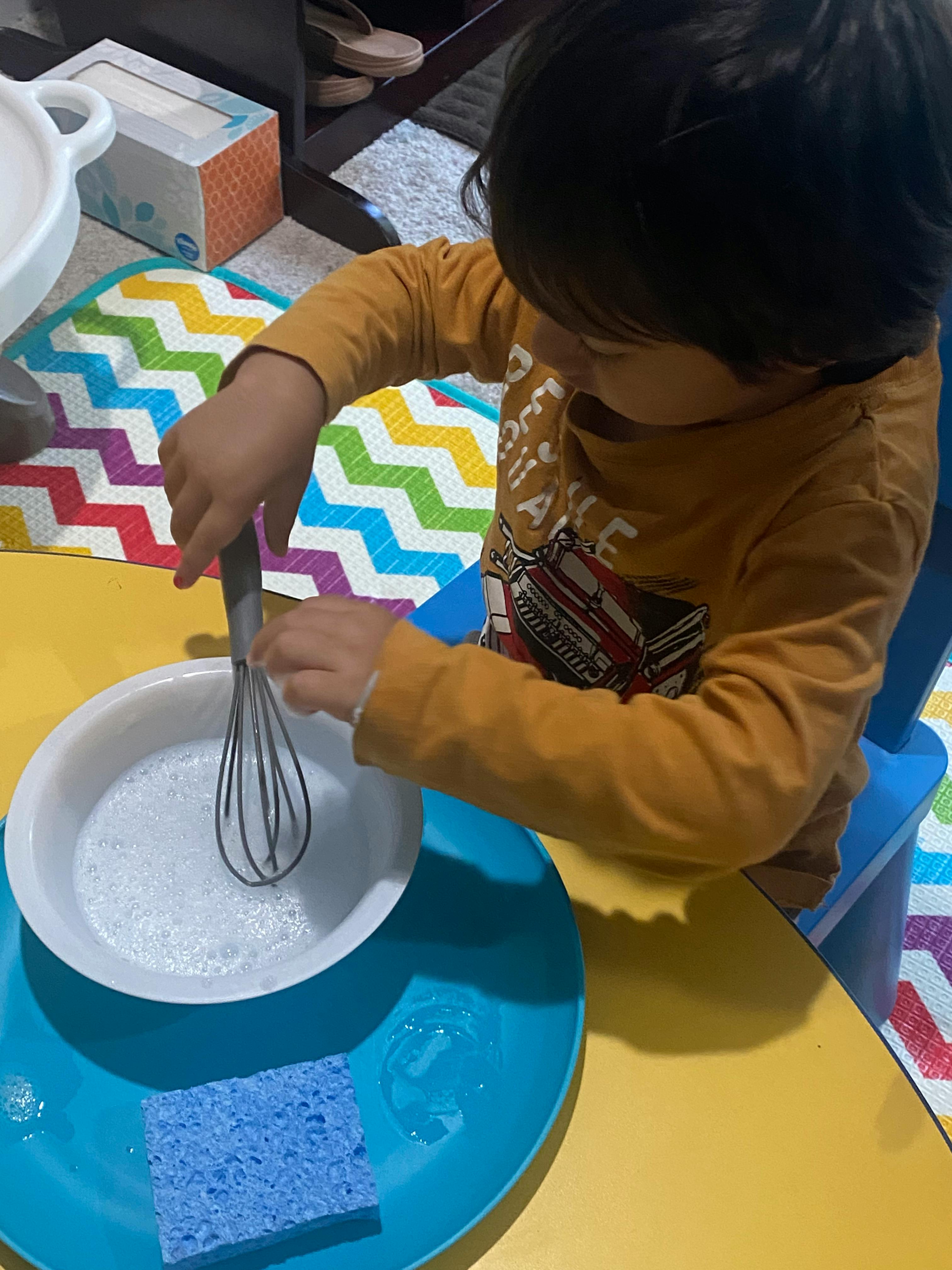 Child whisking soapy water in a bowl