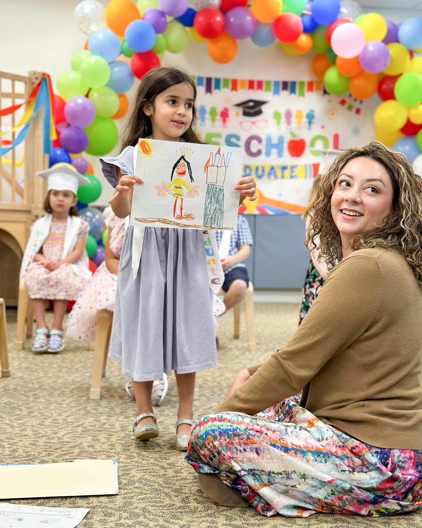 Child holding up a drawing while an adult watches