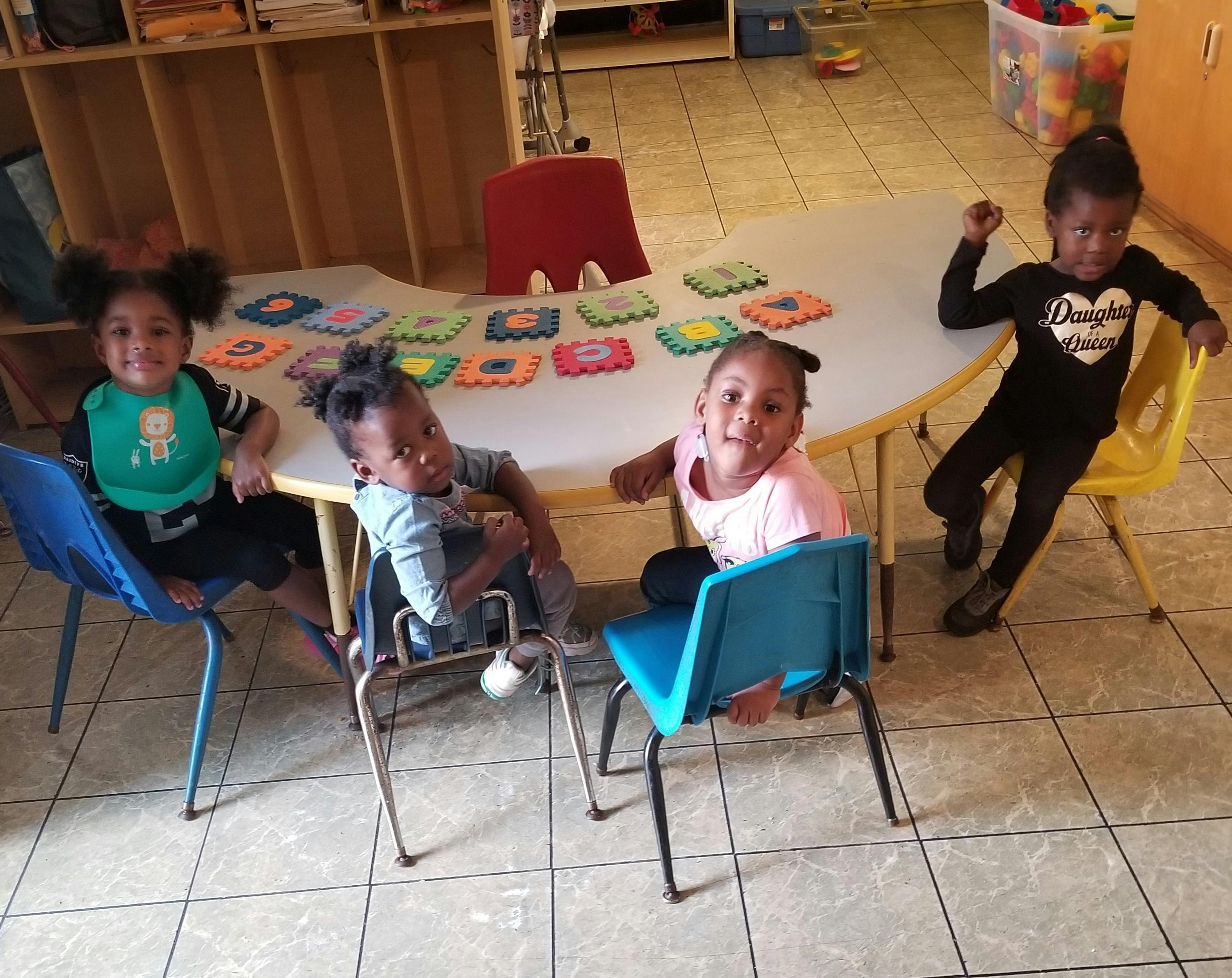 Four children sitting around a table in a classroom