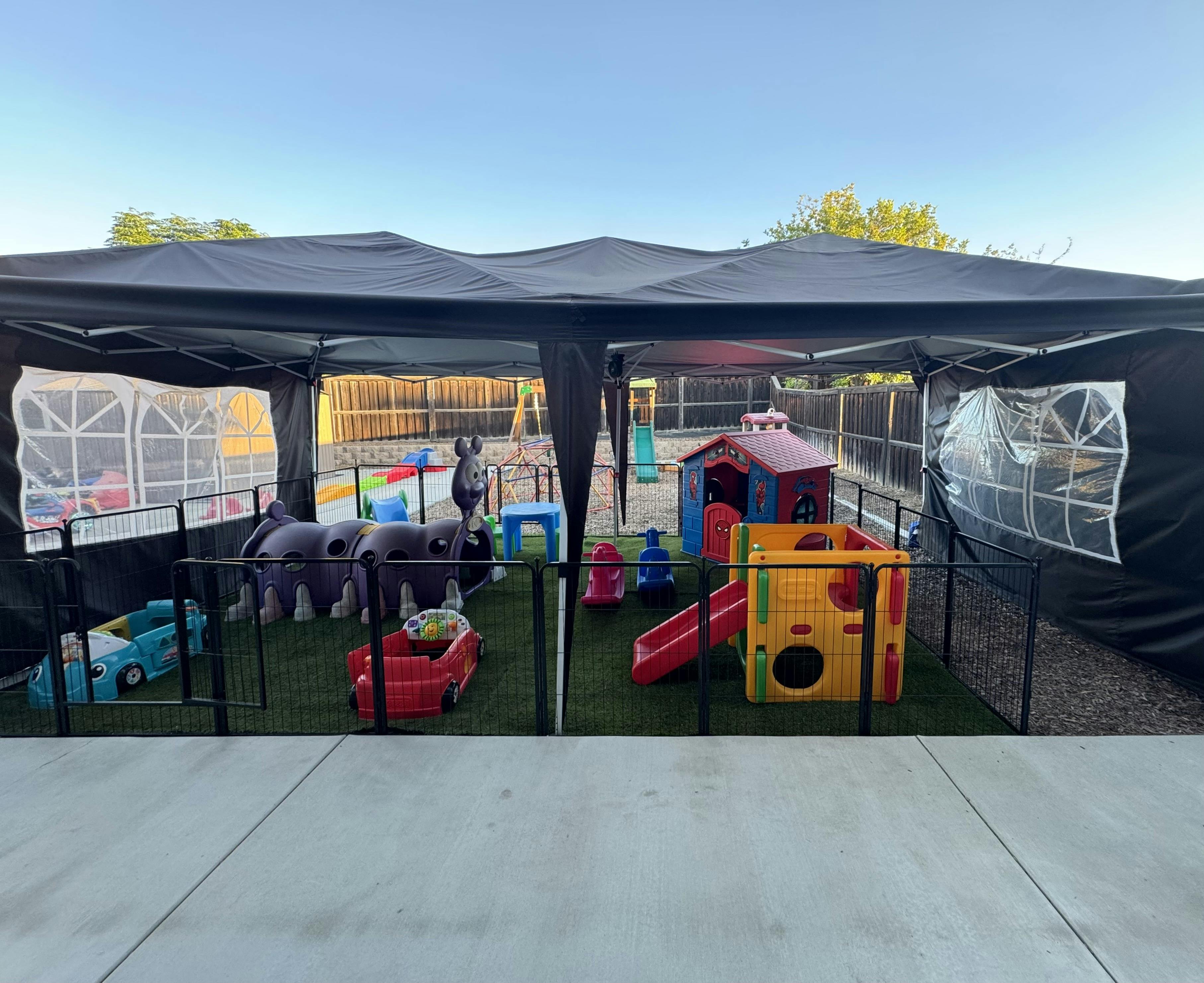 Playground equipment under a black canopy tent