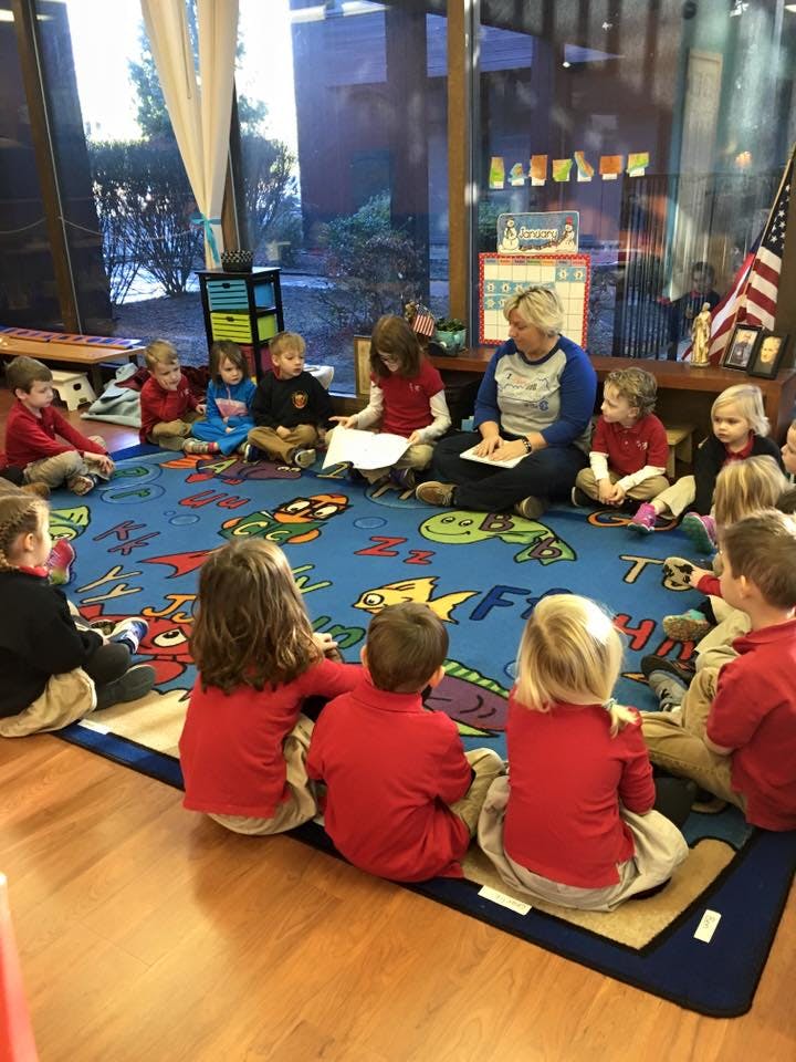 Adult reading to children sitting on a rug in a classroom