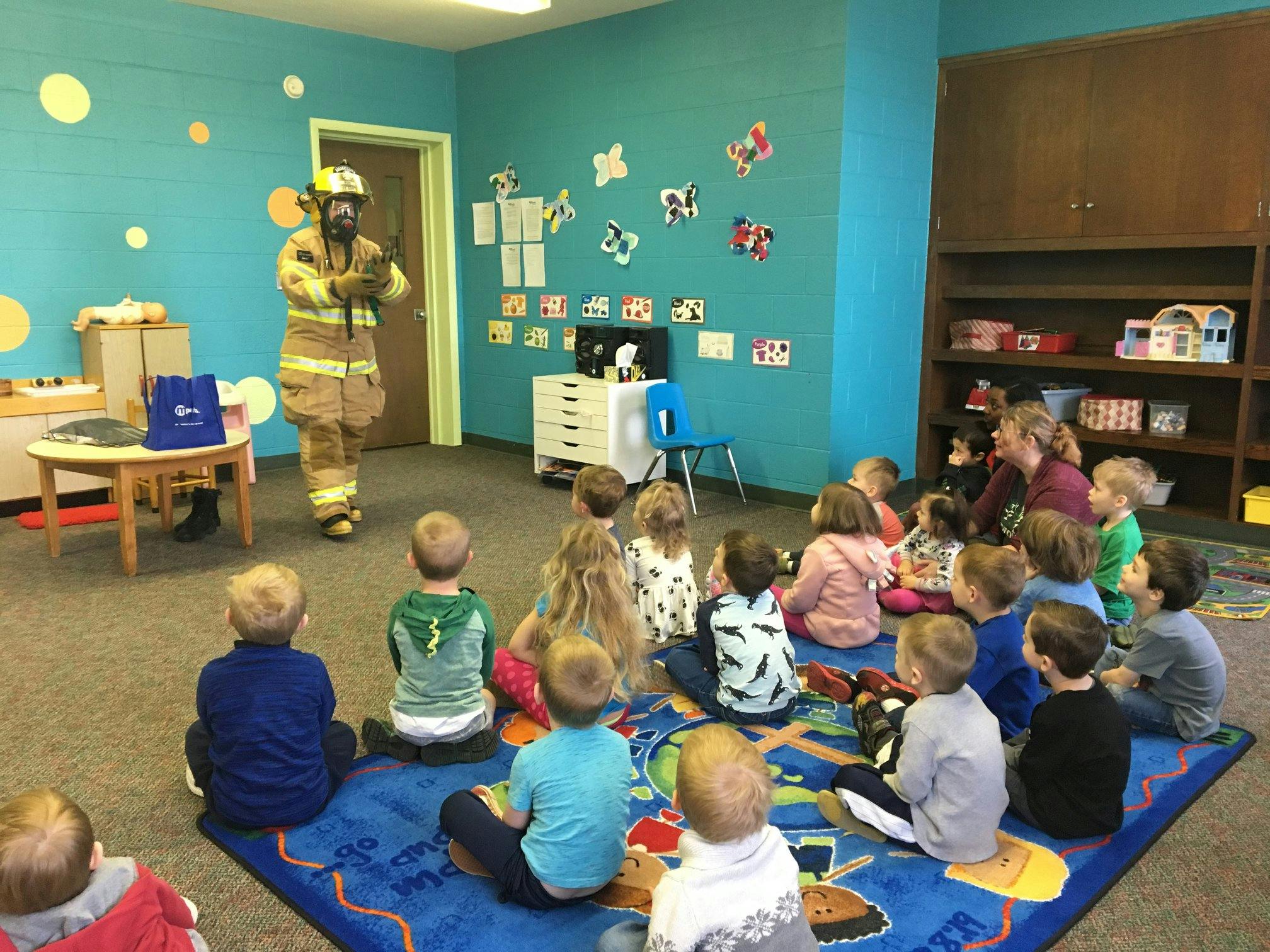 Person in firefighter gear speaking to children in a classroom