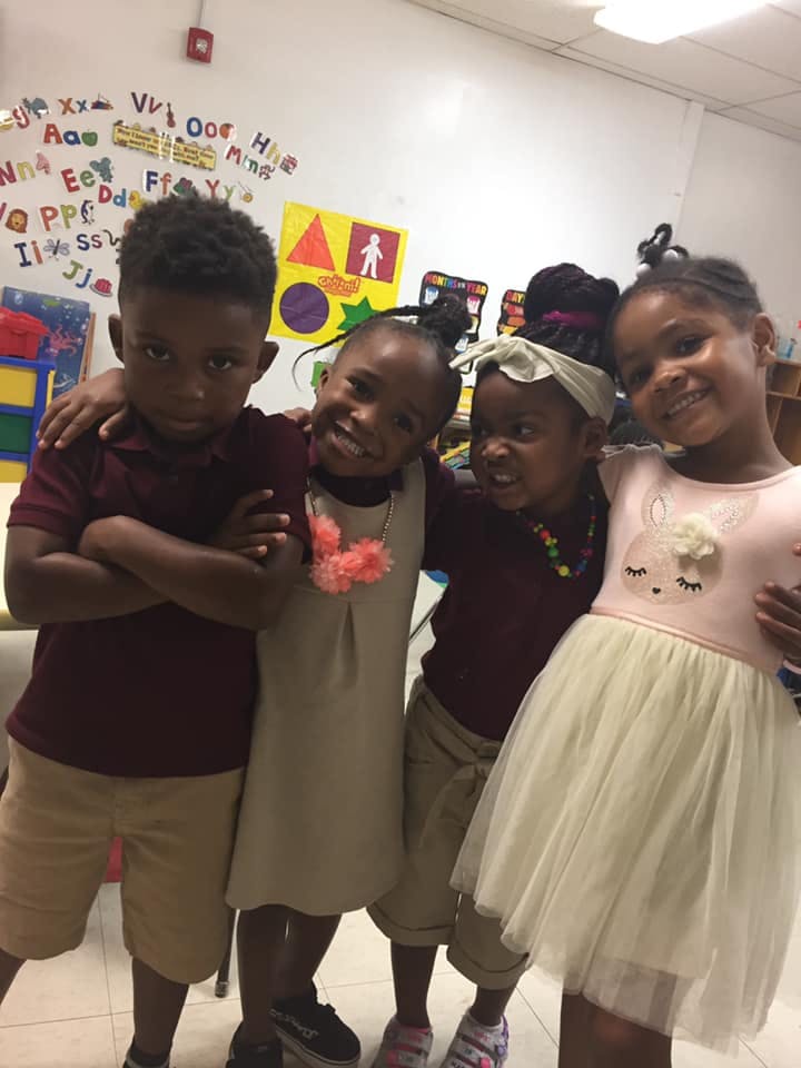 Four children posing together in a classroom