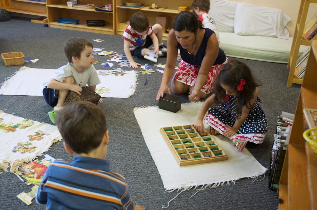 Adult and children on floor playing with puzzles and a wooden game