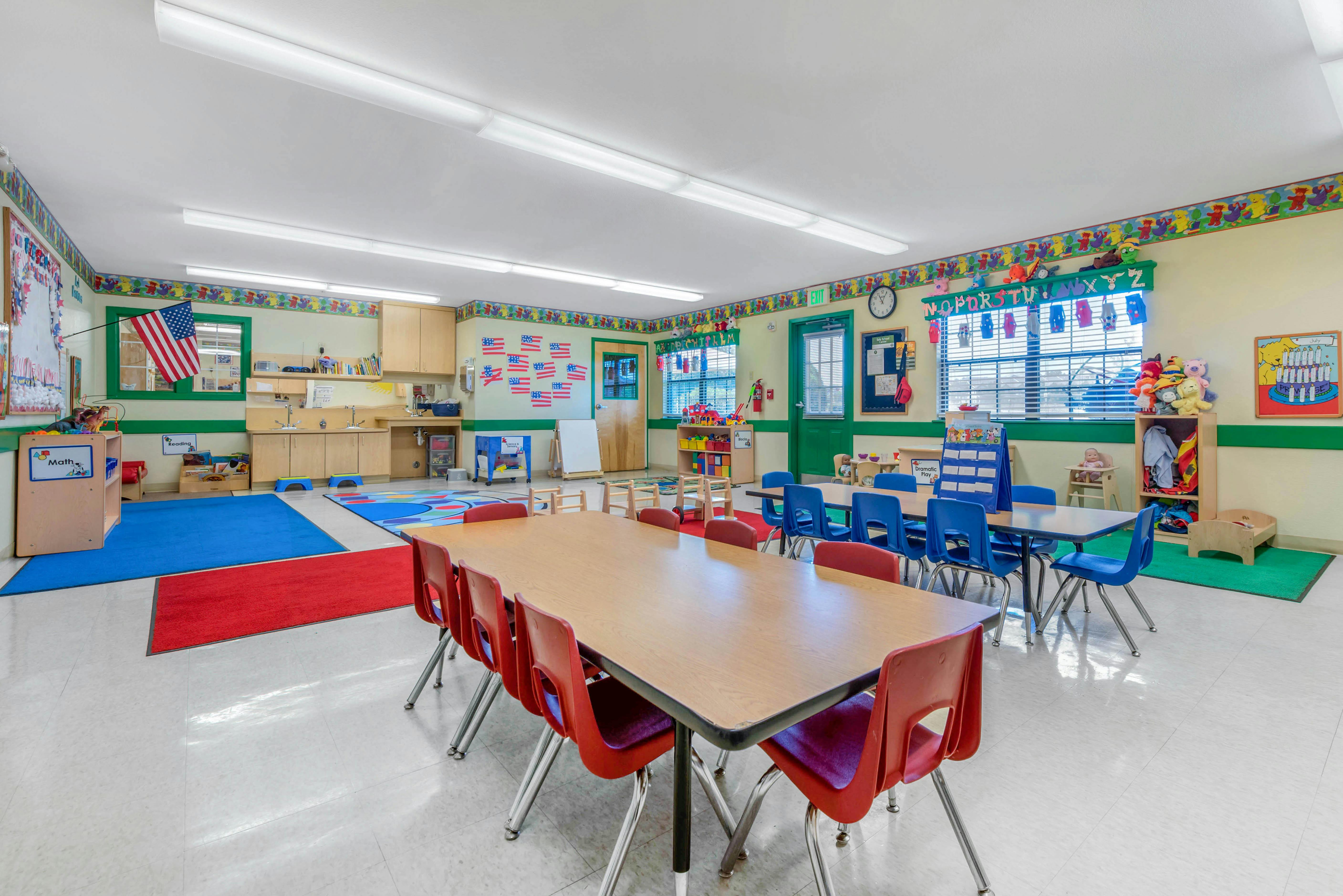 Classroom with child-sized tables, chairs, and colorful rugs on the floor
