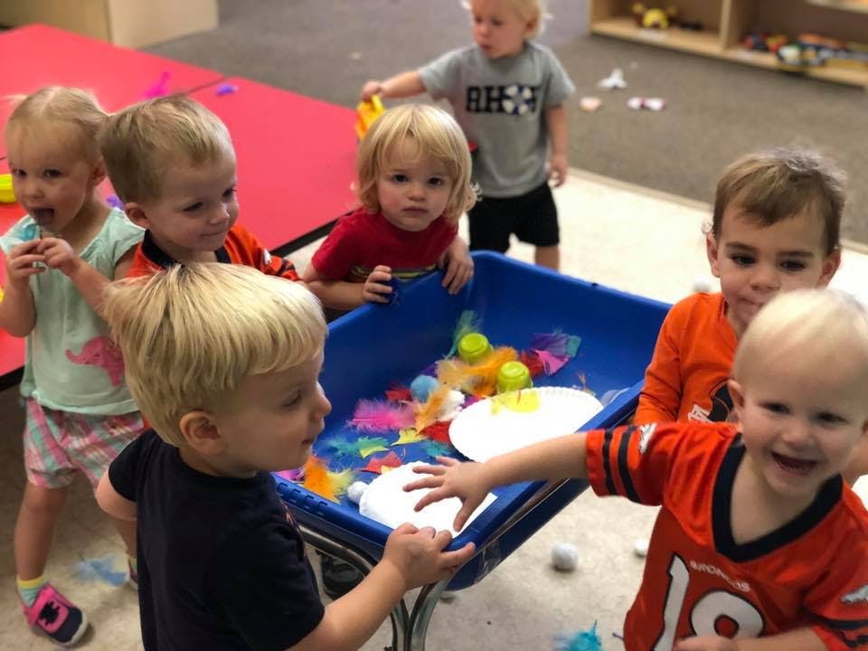 Children playing with colorful items in a blue bin
