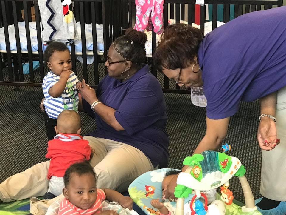 Two people interacting with multiple babies on the floor