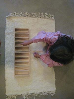 Person on floor working with wooden blocks in a tray