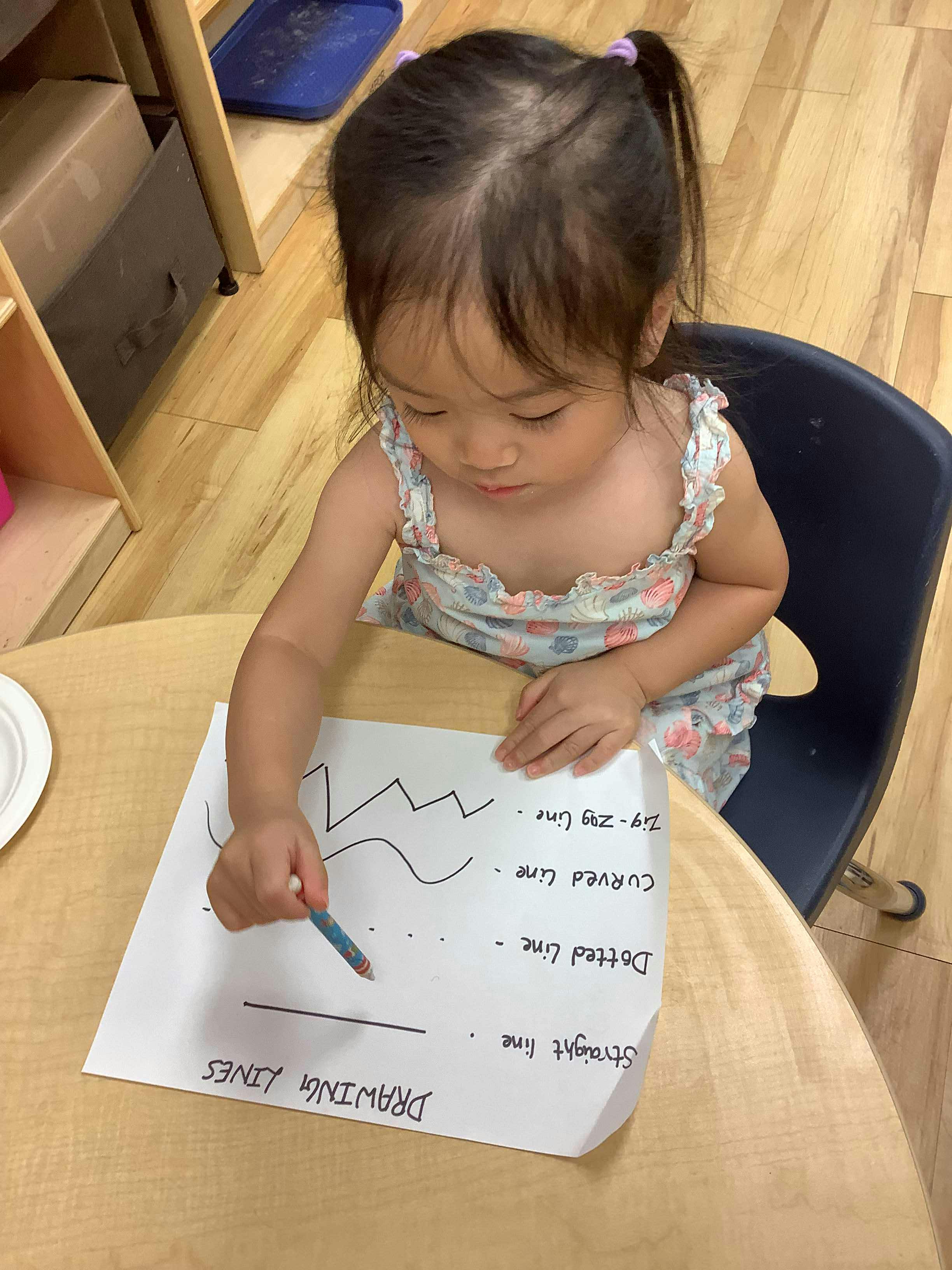 Child drawing lines on a paper with a crayon