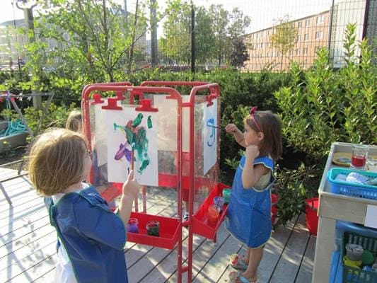 Two children painting at easels outdoors