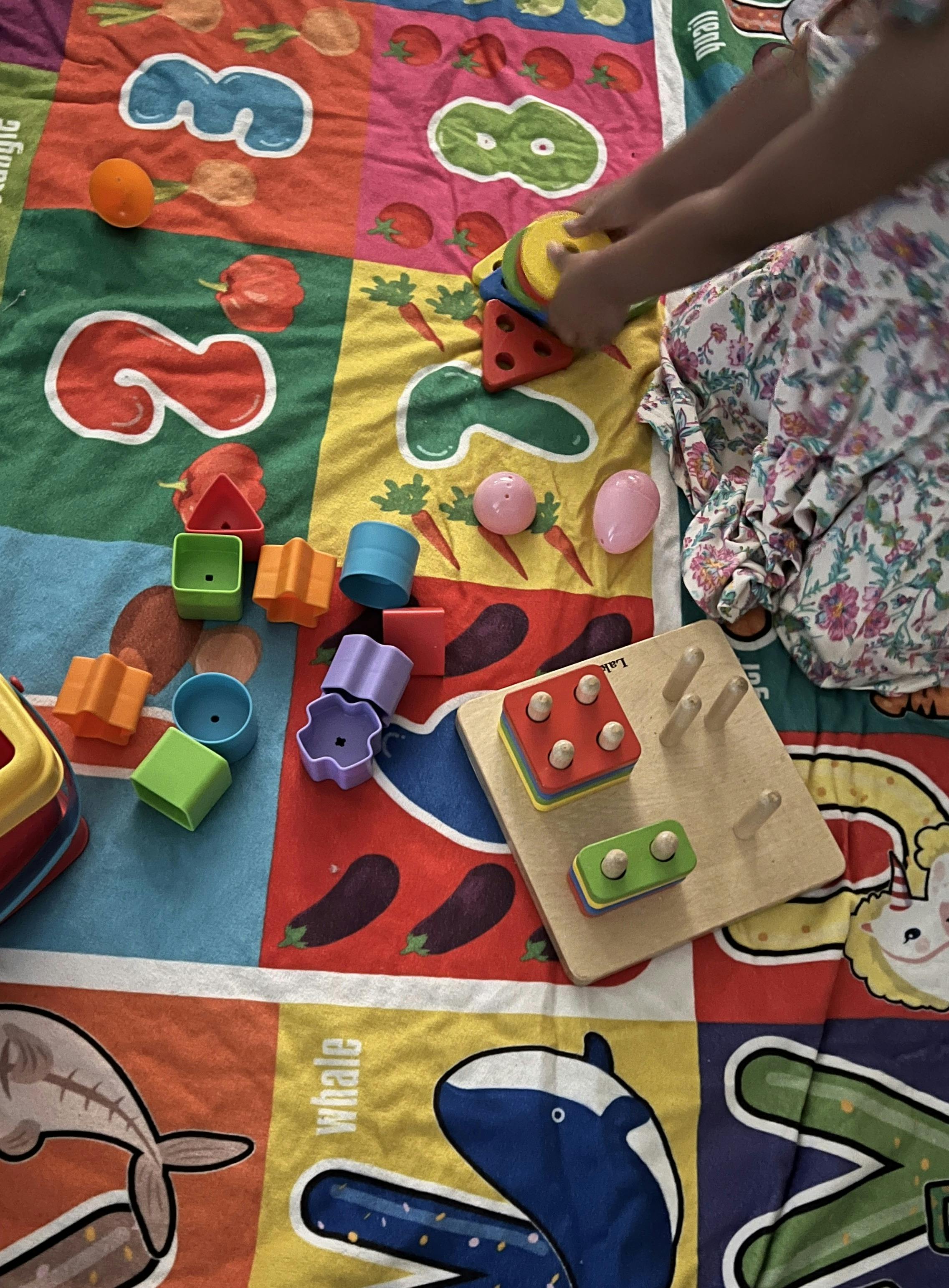 Child playing with colorful stacking shapes on a patterned mat