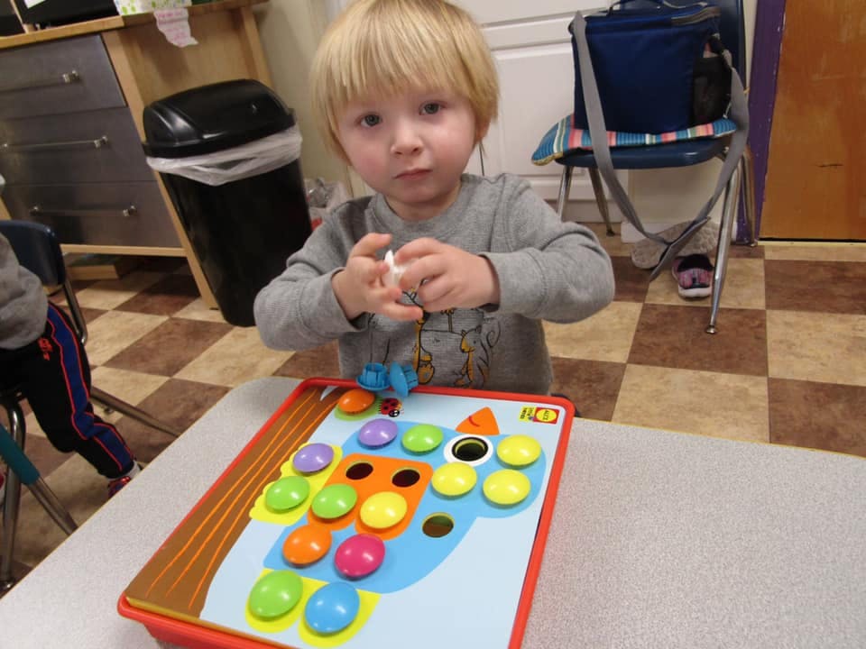 Child playing with a colorful peg board toy