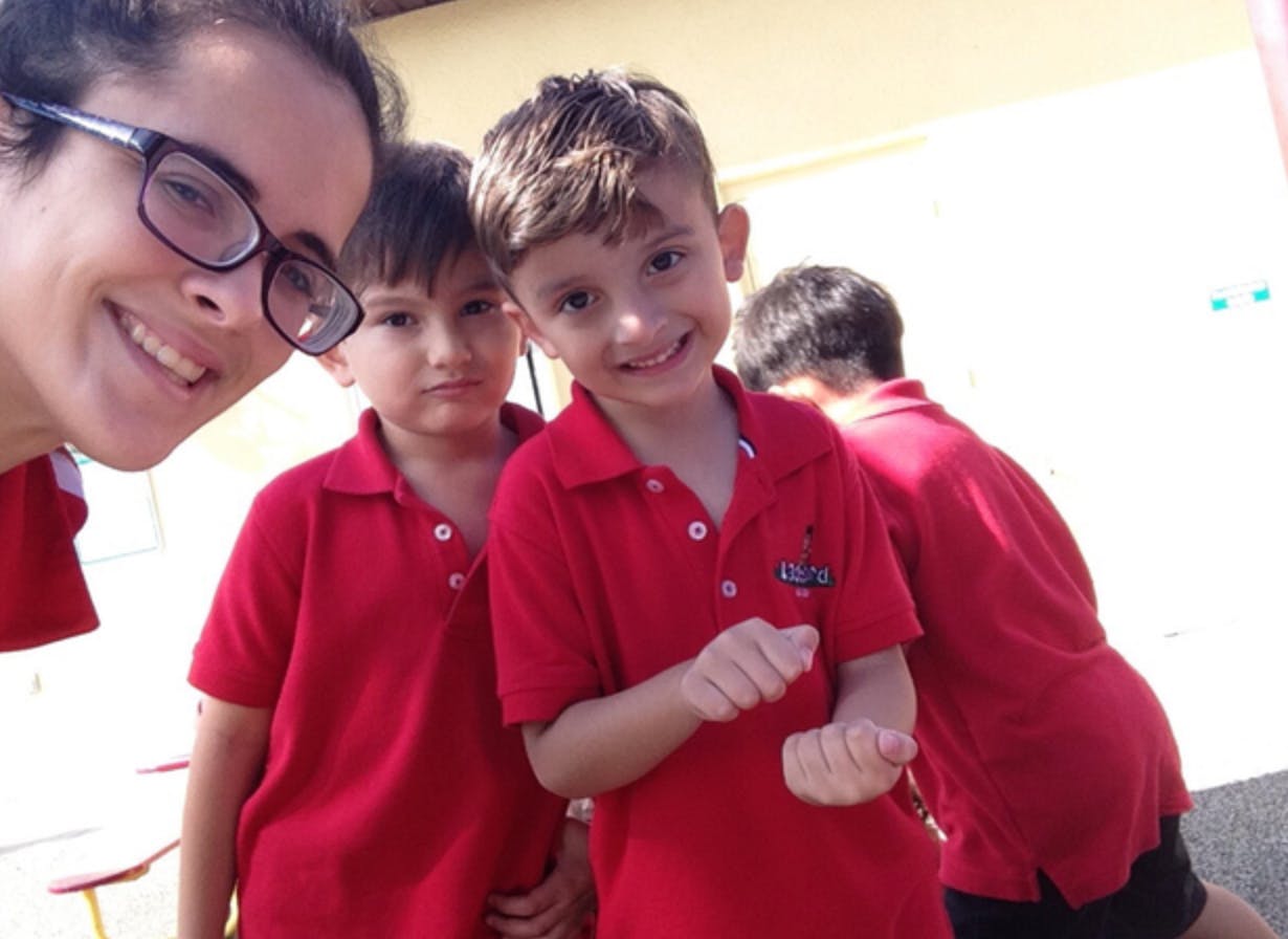 Person in glasses with two children in red shirts