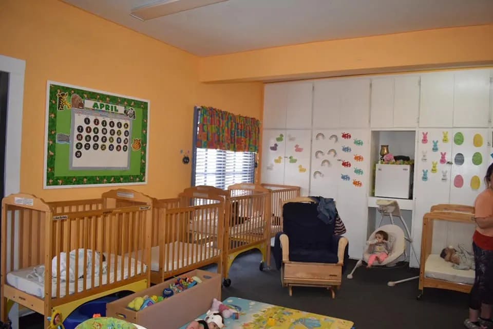 Nursery room with multiple wooden cribs and a calendar on the wall