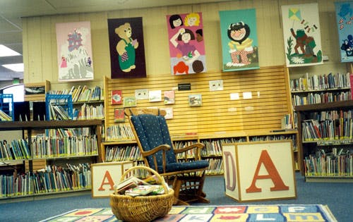 Children's library with a rocking chair, bookshelves, and large letter blocks