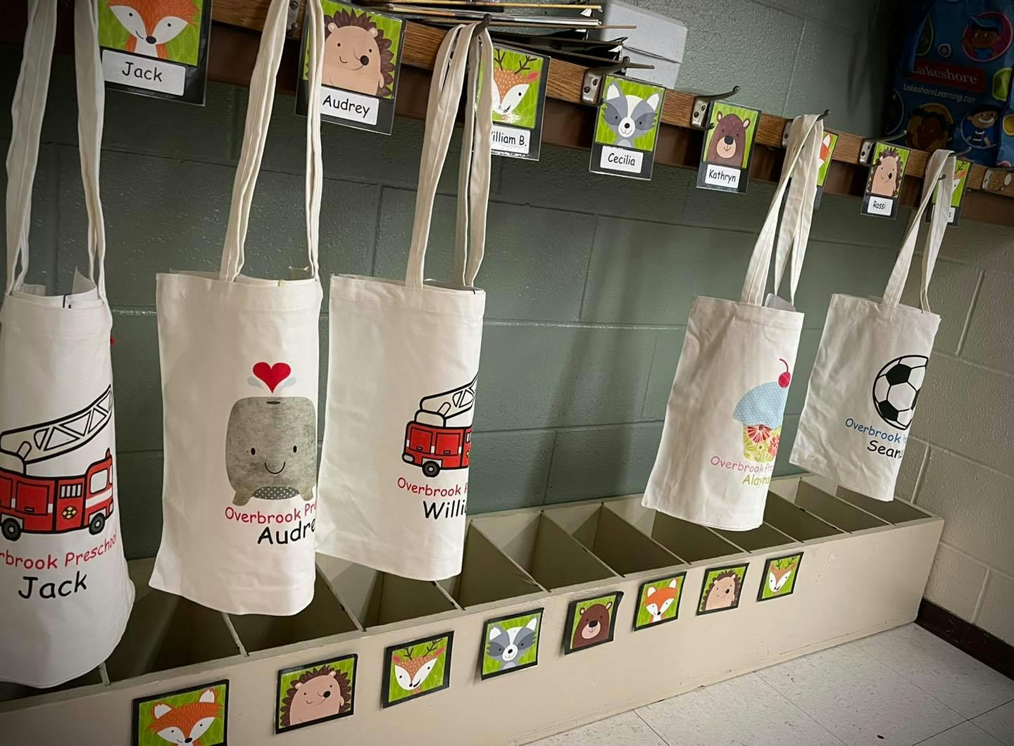 Tote bags with various designs hanging above cubbies