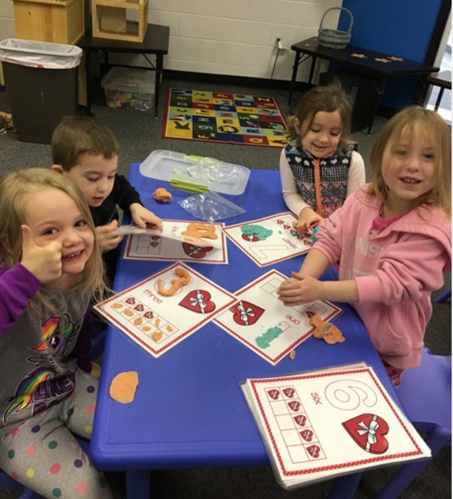 Four children at a table with activity sheets and craft sheets