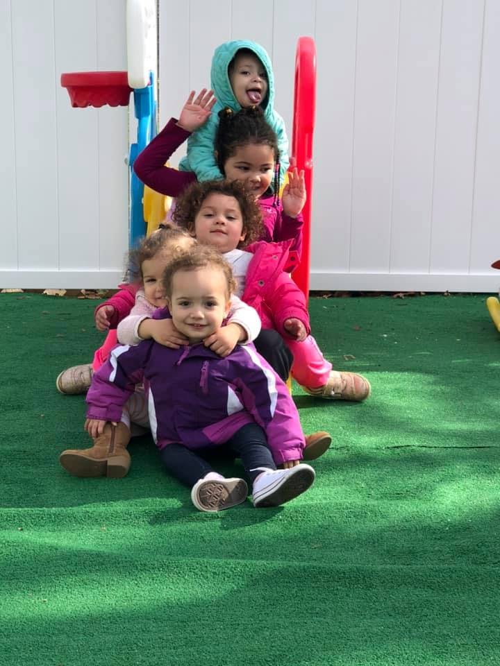 Multiple children sitting on a small slide