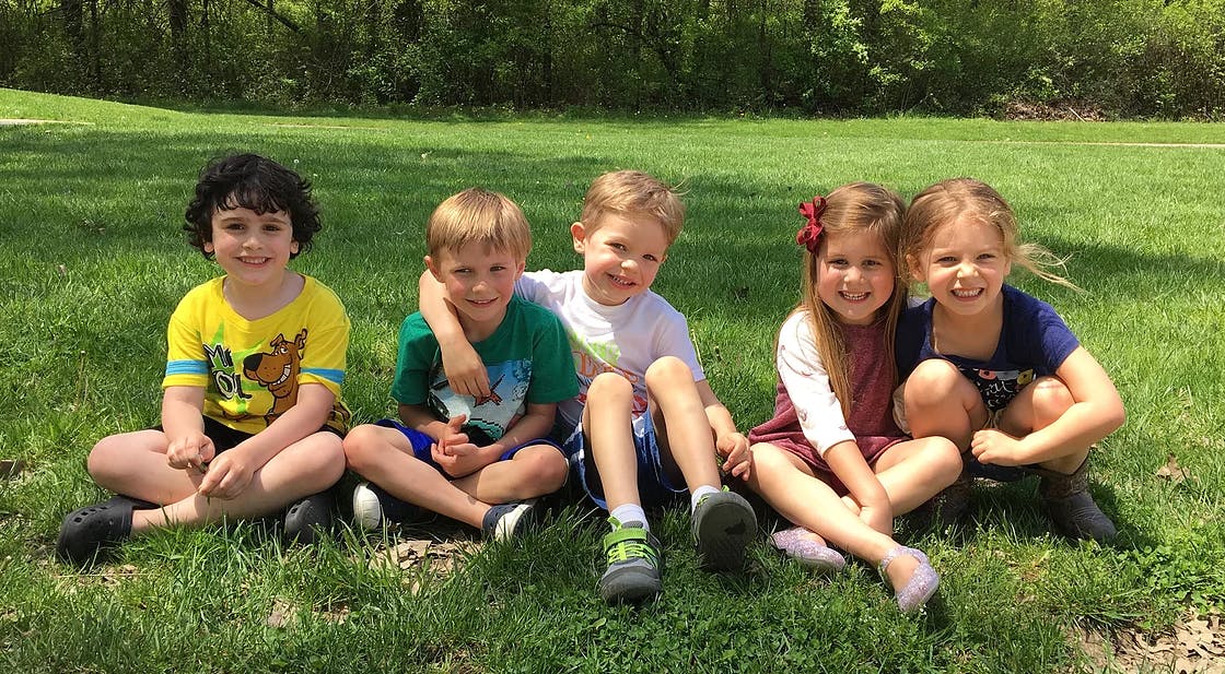 Five children sitting on grass outdoors