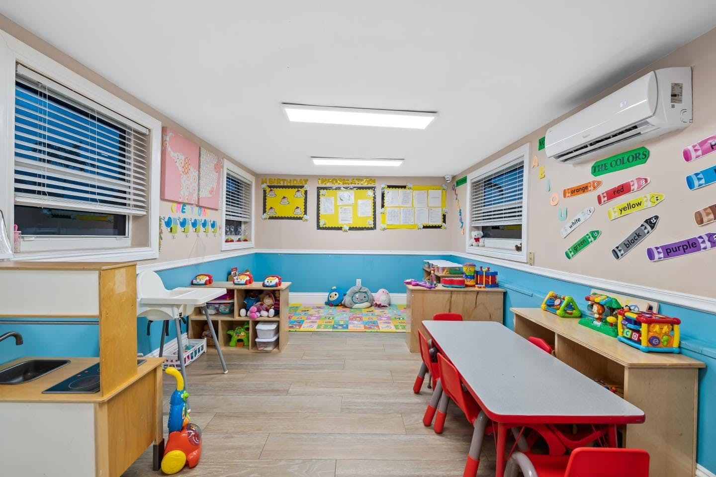 Empty classroom with small tables and chairs, toys, and colorful decorations
