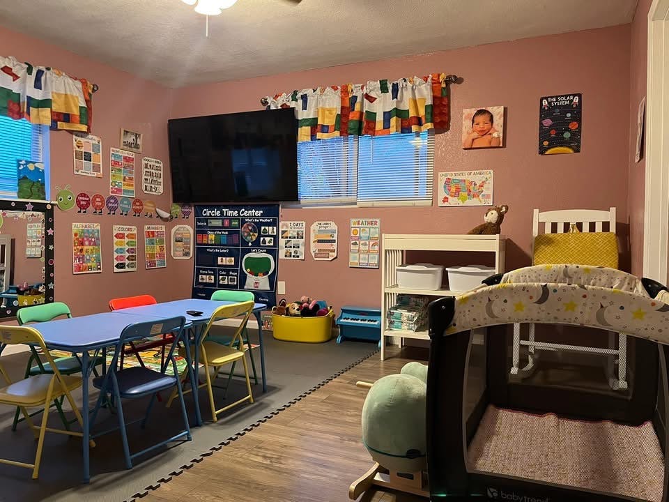 Classroom or nursery with a table and chairs, playard, and educational posters