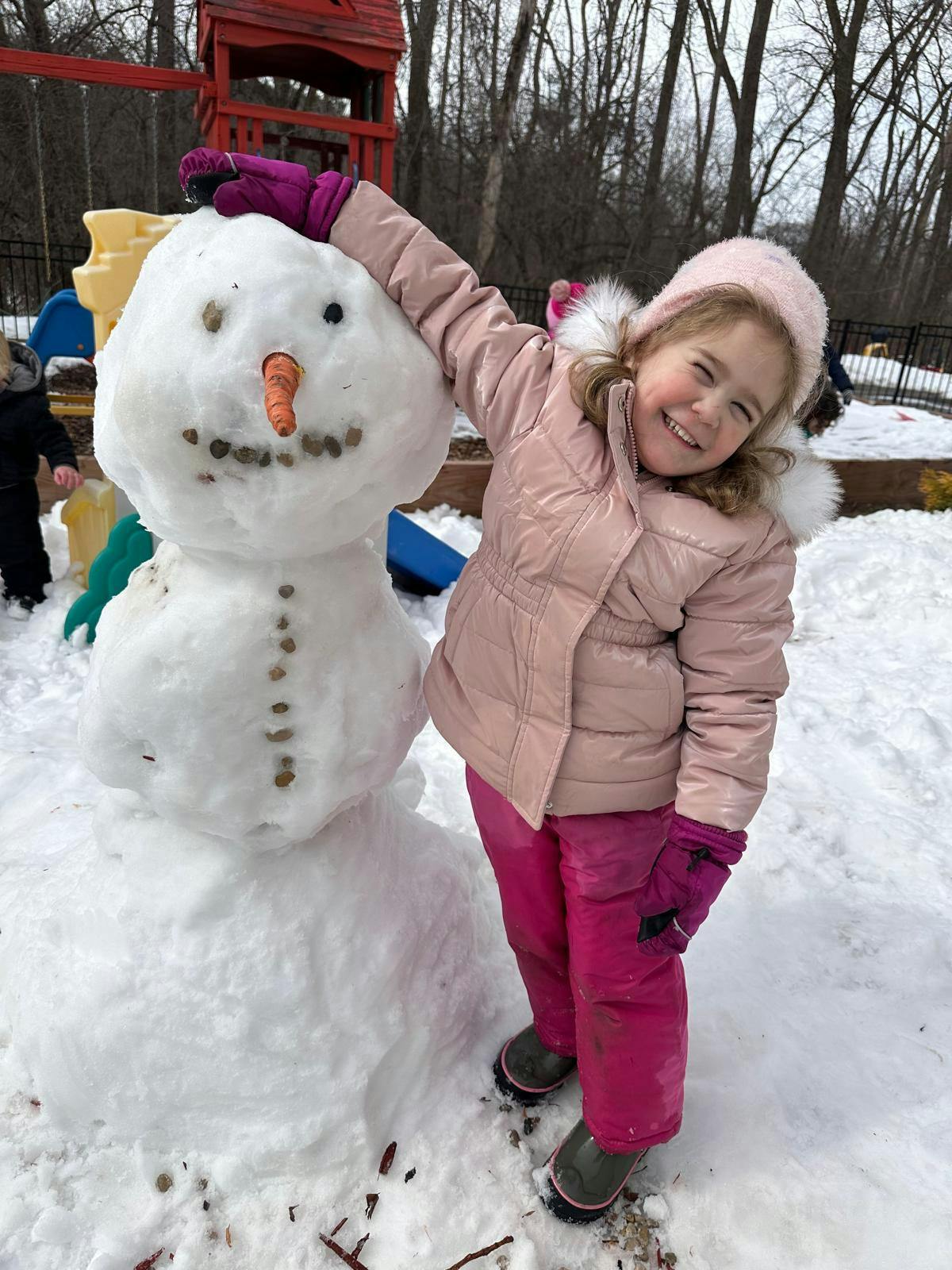 Child standing next to a snowman