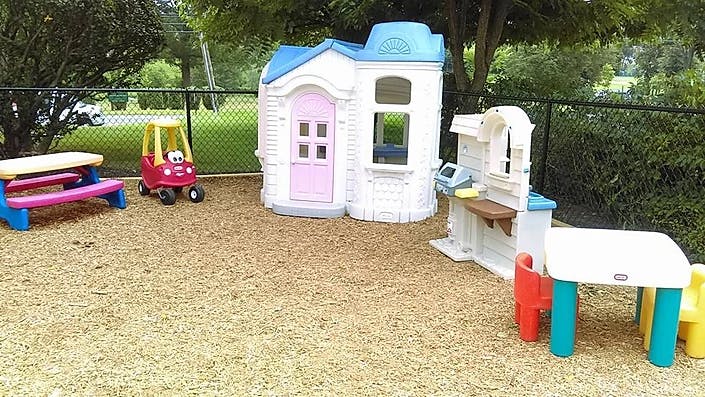 Outdoor play area with a playhouse, toy car, picnic table, and play kitchen