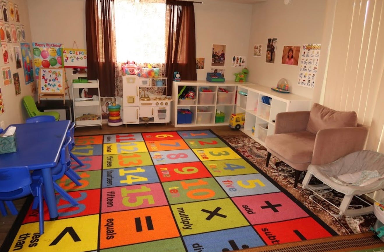 Playroom with colorful number and math symbol rug, blue table, and storage shelves