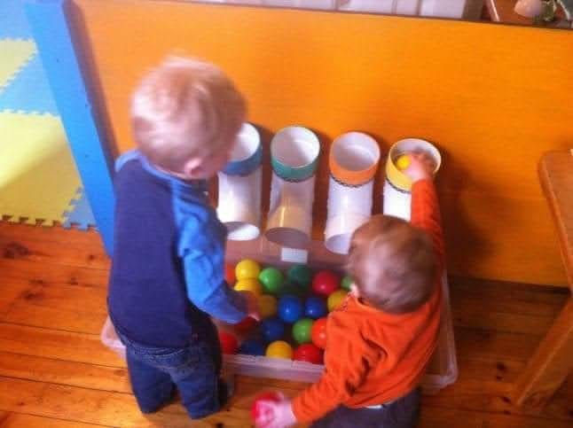 Two children playing with a ball drop toy
