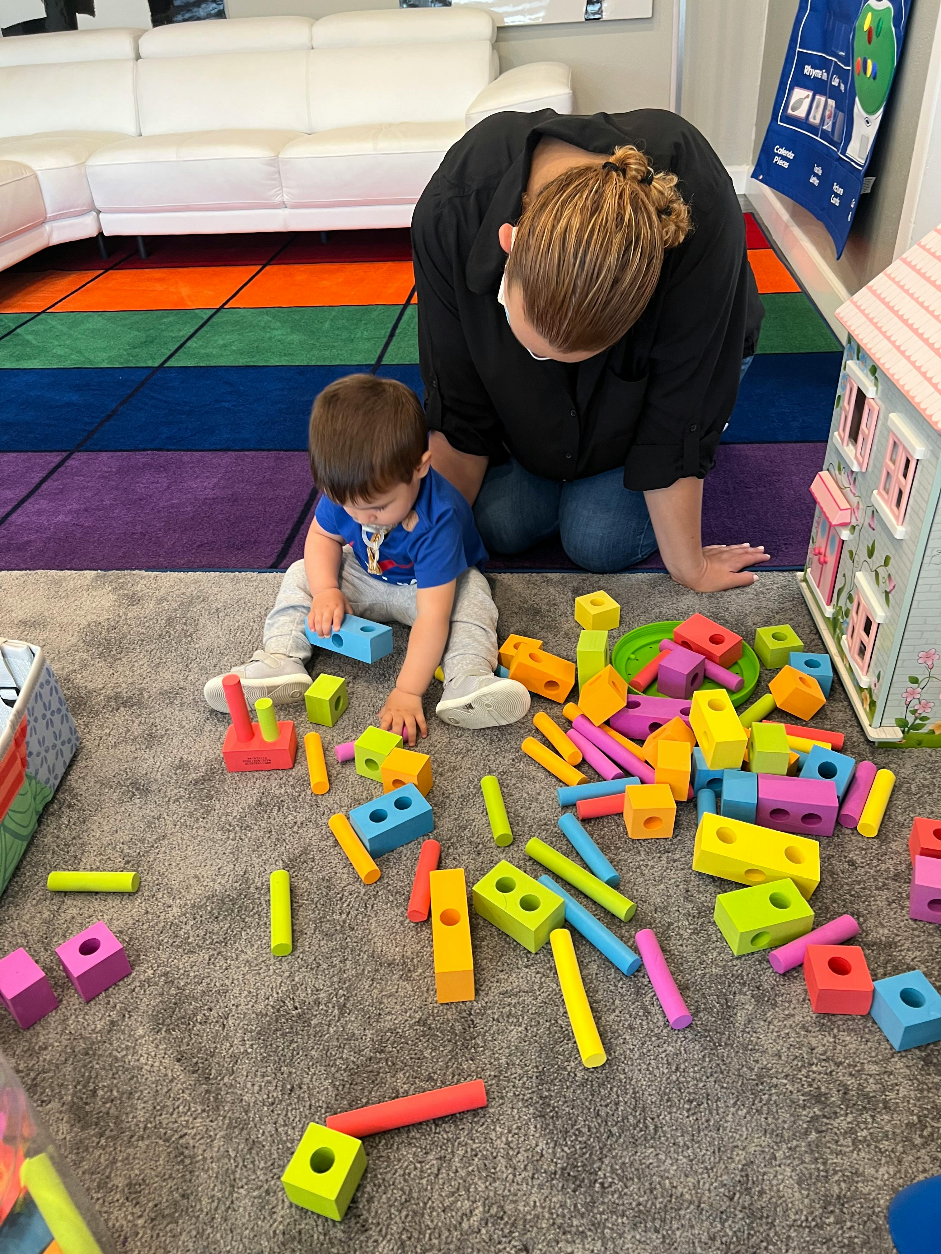Adult and child playing with colorful building blocks on a rug