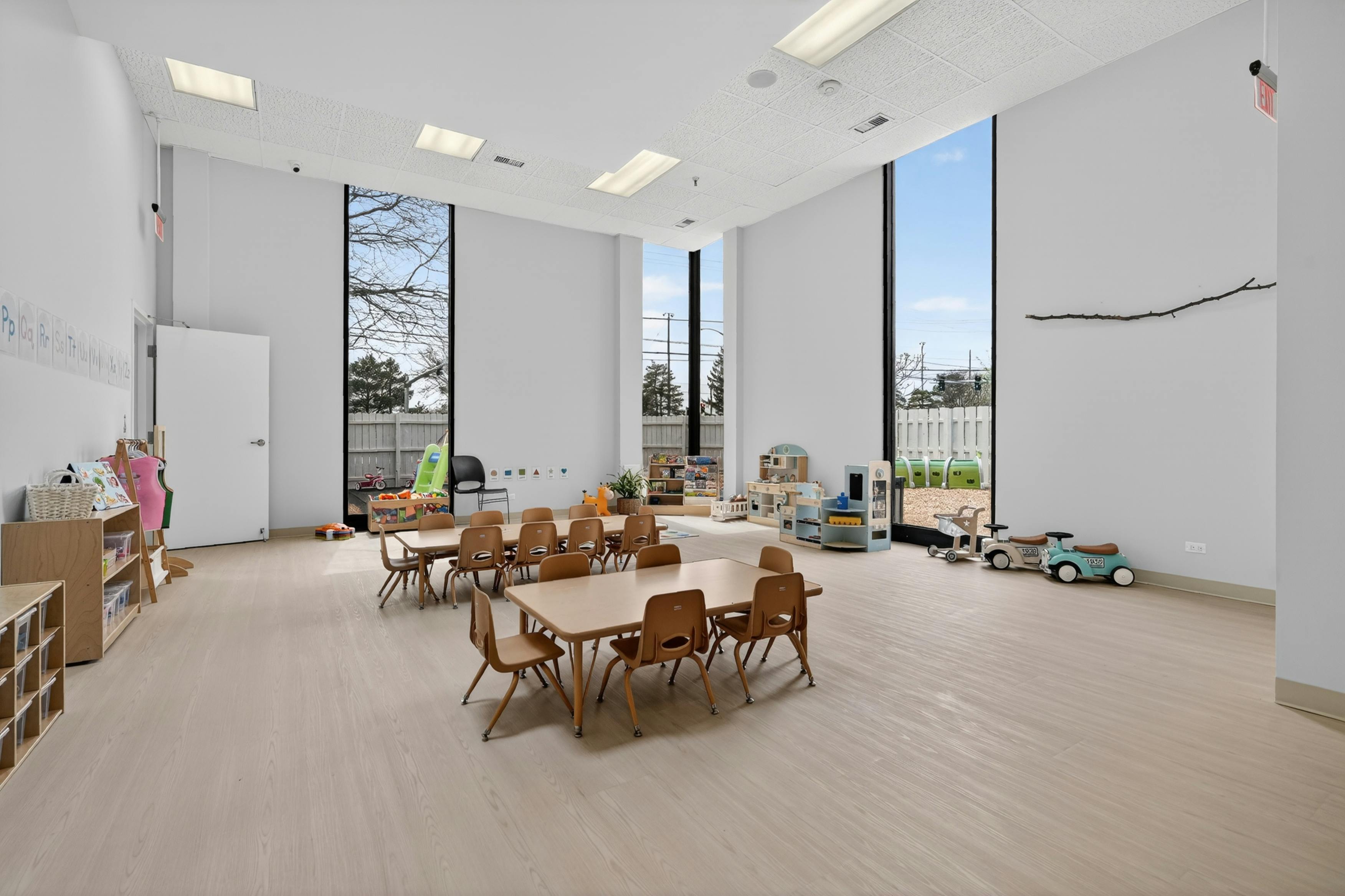 Spacious preschool classroom with tables and children's play equipment