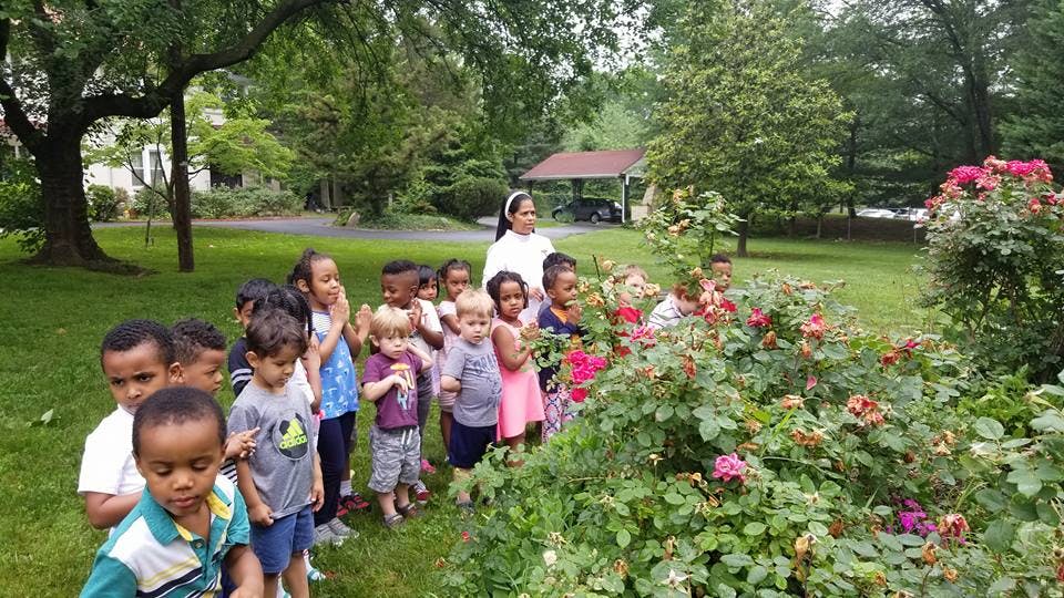 Adult and children standing near a flowering bush outdoors