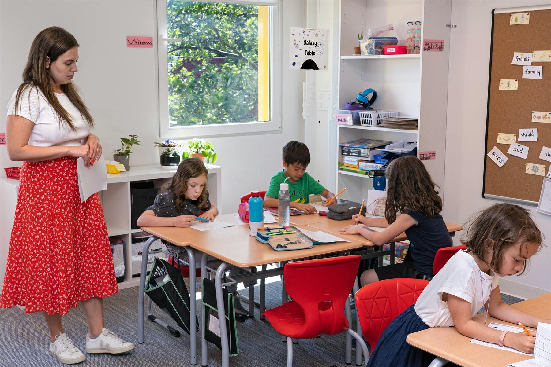 Person standing in a classroom with children at desks