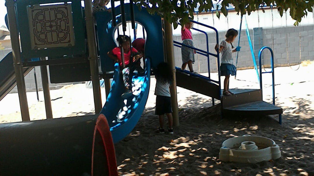 Children playing on a blue slide and climbing structure at a playground