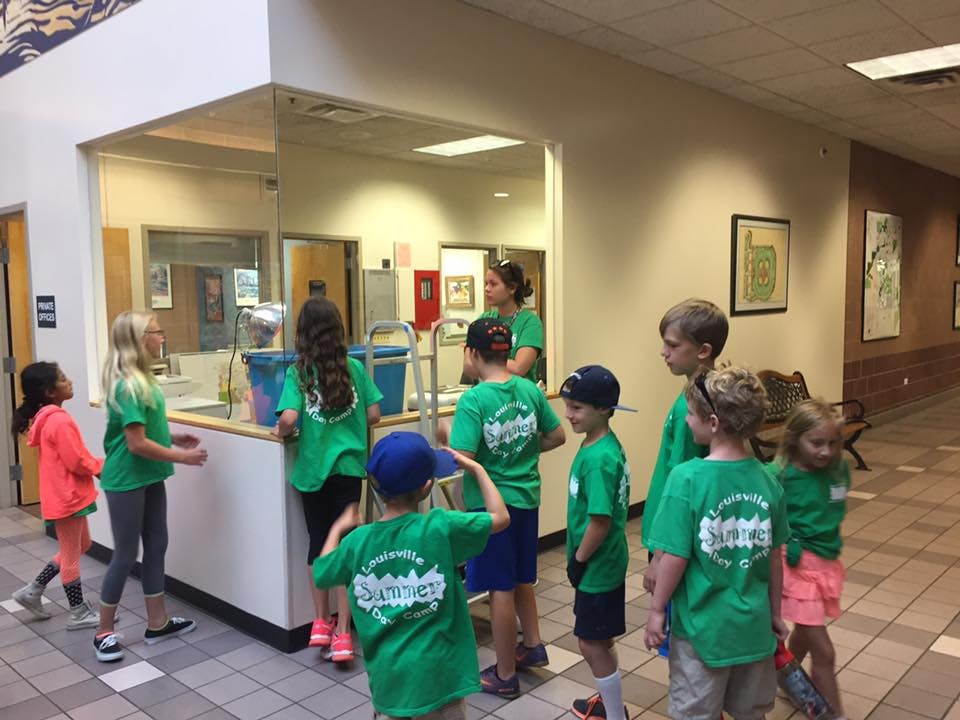 Children and adults in green shirts gathered around a counter