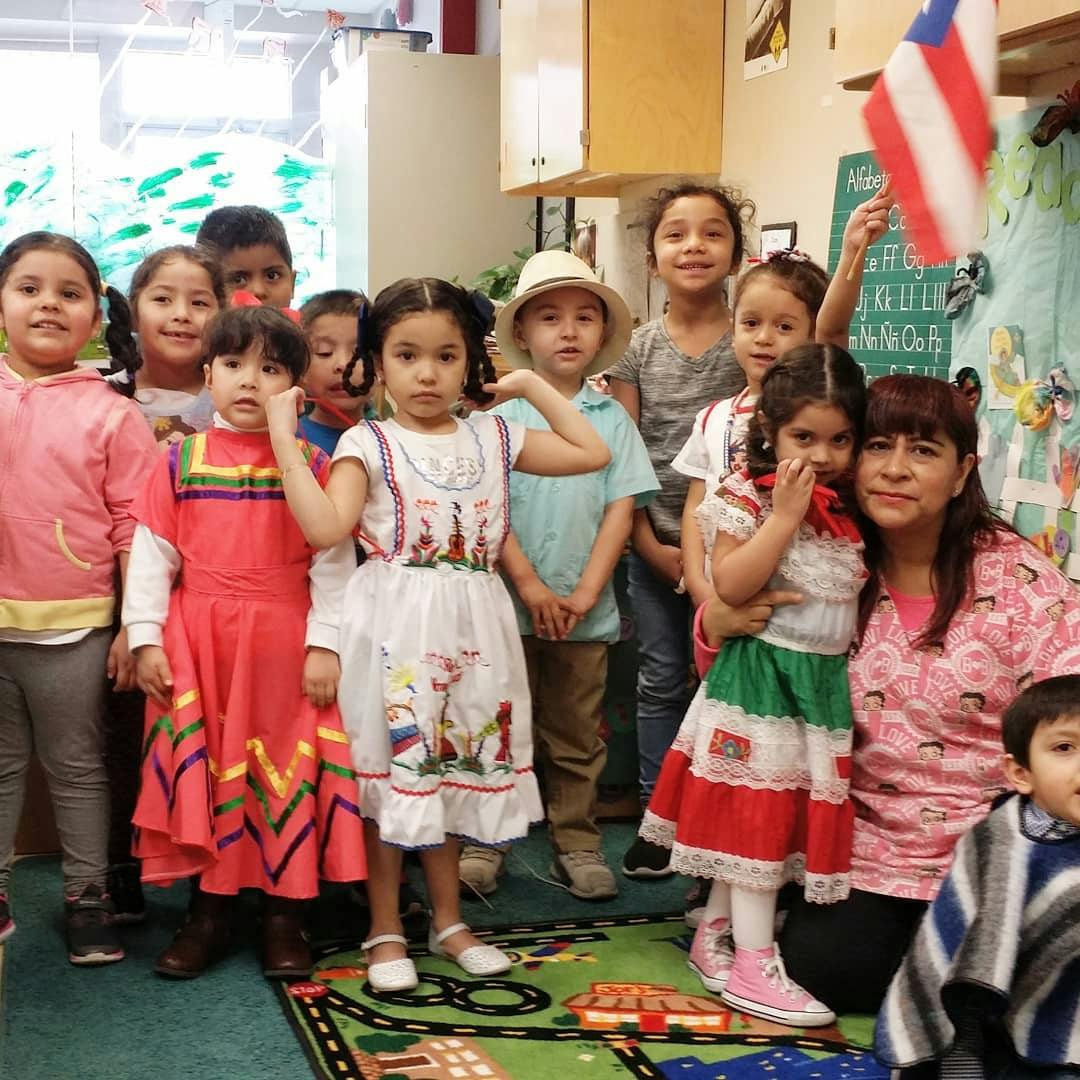 Group of children and an adult posing in a classroom