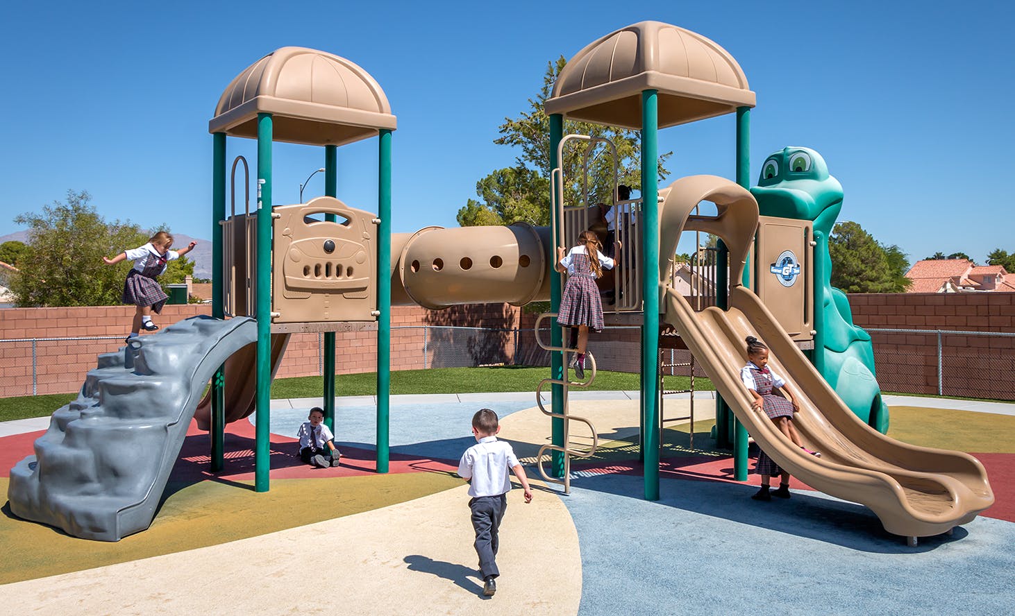 Children playing on a playground structure with slides and climbing areas