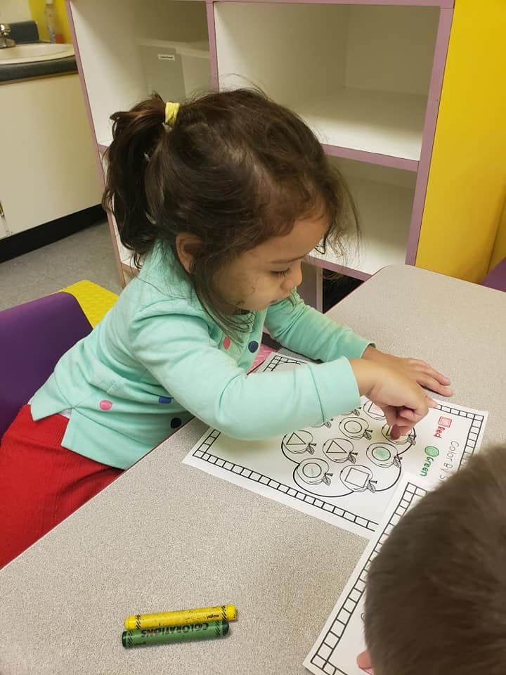 Child coloring a worksheet at a table