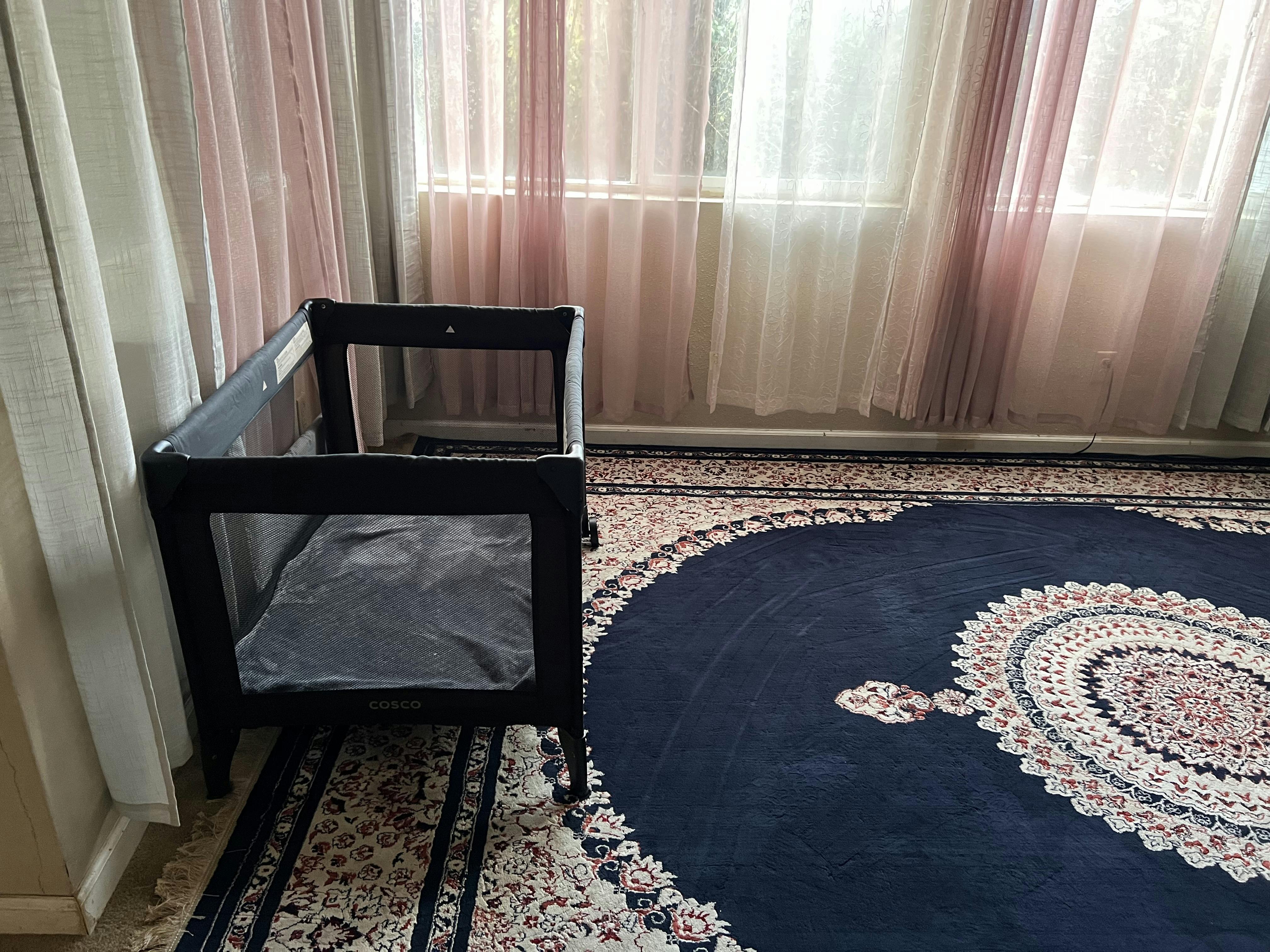 Portable crib with a blanket on a patterned rug