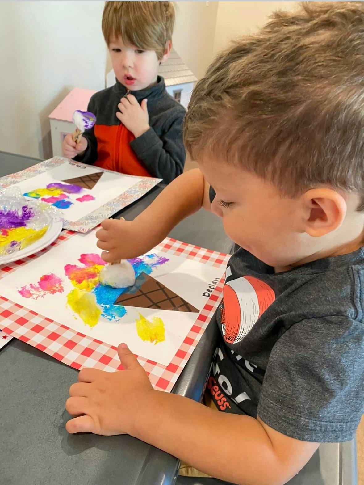 Two children making colorful ice cream cone crafts