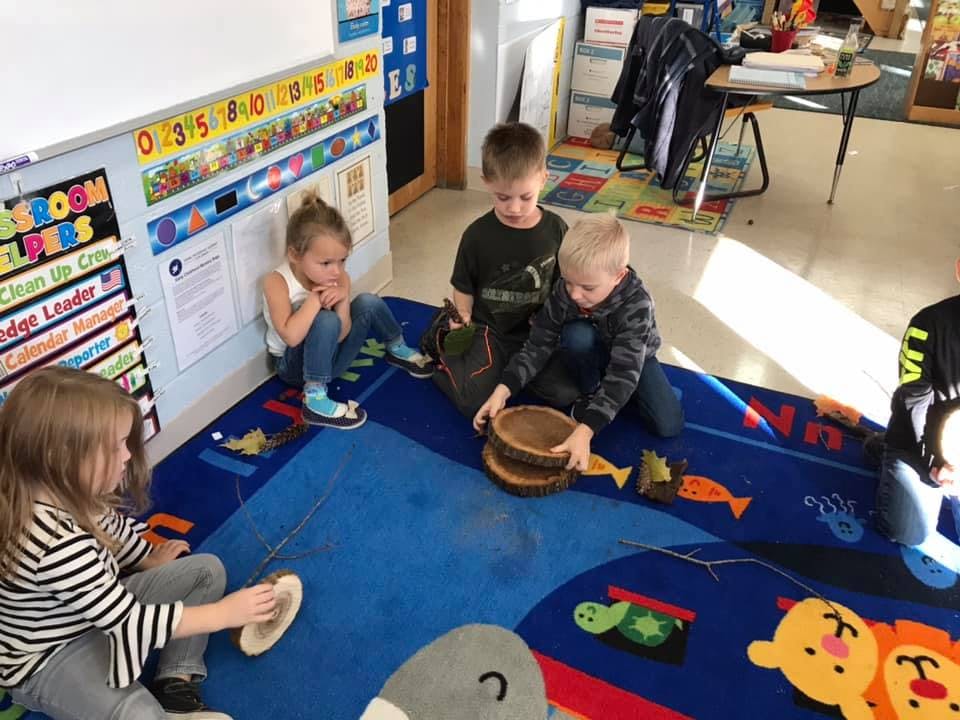 Four children playing on a blue rug in a classroom