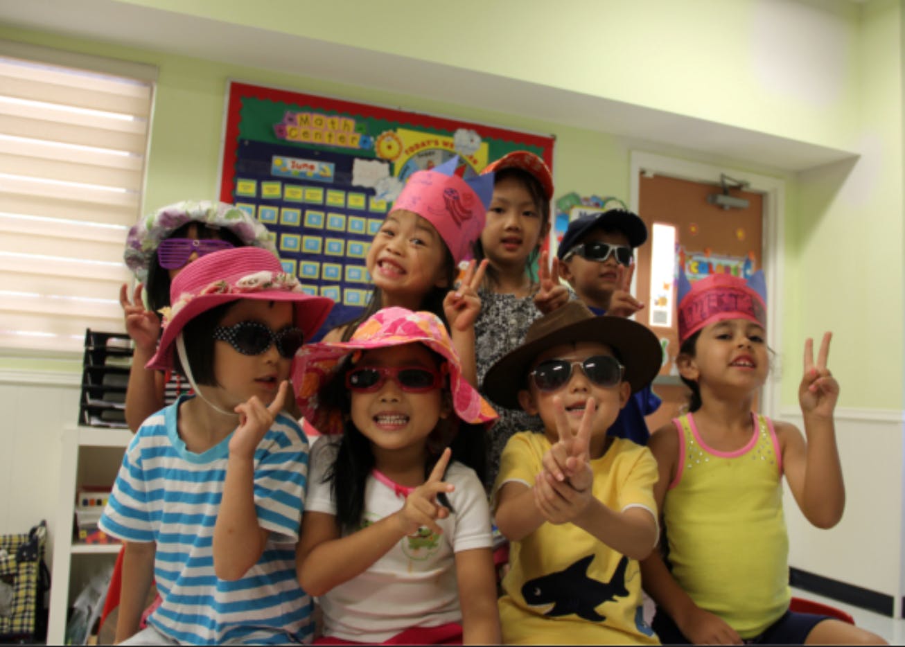 Group of children wearing hats and sunglasses, making peace signs